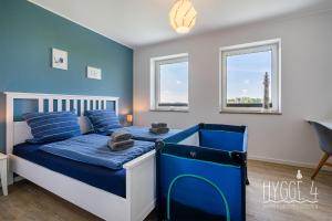 a bedroom with a blue and white bed and two windows at Ferienhaus Hygge4 in Carolinensiel