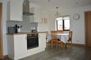 a kitchen with white cabinets and a table with chairs at Kilronan Self Catering - Eoropie, Isle of Lewis in Eoropie