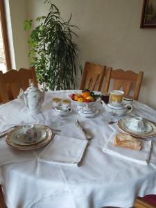 una mesa con platos y tazas y un bol de fruta en LA PETITE MAISON DU SABOT en Langonnet