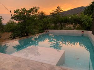 a swimming pool with a sunset in the background at Finca Las Fuentezuelas in Carataunas