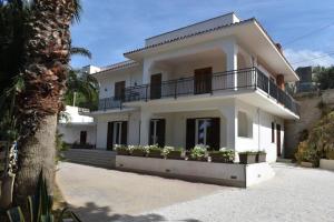 a white house with potted plants in front of it at b&b Lastracu in Castellammare del Golfo
