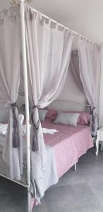 Cama con dosel con cortinas blancas y sábanas rosas en Villa Katarin en Komiža