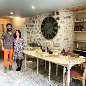 a man and a woman standing next to a table with food at Les Herbes de la Saint Jean in Saint-Bonnet-le-Froid
