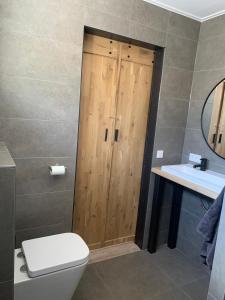 ein Badezimmer mit einem WC und einer Holztür in der Unterkunft DOCK10TEXEL in De Cocksdorp