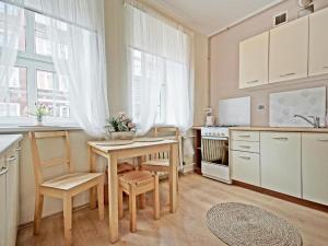 グダニスクにあるApartament Kameralny 17のキッチン(テーブル、椅子付)、キッチン(白いキャビネット付)