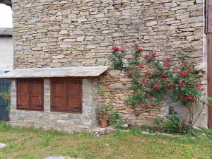 un bâtiment en pierre avec des roses sur son côté dans l'établissement Pelagallo, à Bagnolo Piemonte