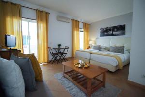 una camera con letto e un soggiorno con divano di Oasis Beach Apartments a Luz