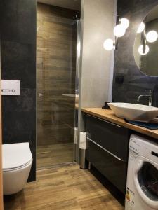 a bathroom with a toilet and a sink and a washing machine at Apartament Centrum Bocian in Białystok
