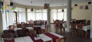 un comedor con mesas, sillas y ventanas en Alpine Garden Hotel (Trayanovi Dvori), en Simitli