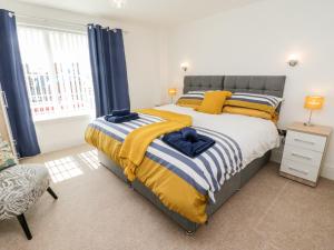 um quarto com uma cama grande com lençóis amarelos e azuis em Sail Away, 17 Union Mill em Whitby