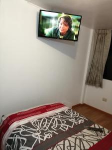 1 dormitorio con TV de pantalla plana en la pared en La Casa de Leonardo YANAHUARA, en Arequipa