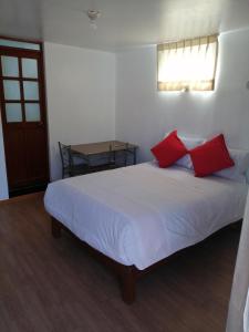 Un dormitorio con una cama con almohadas rojas y una mesa. en La Casa de Leonardo YANAHUARA, en Arequipa