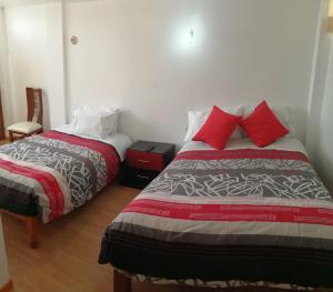 1 dormitorio con 2 camas y almohadas rojas en La Casa de Leonardo YANAHUARA, en Arequipa