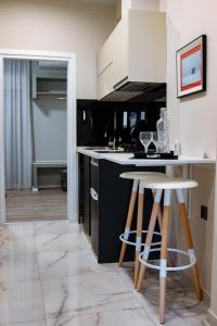 une cuisine avec des placards blancs et deux tabourets de bar dans l'établissement Calma Suite (Cielo suites), à Kavala