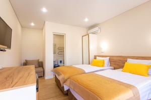 two beds in a hotel room with yellow pillows at Parfenon in Divnomorskoye