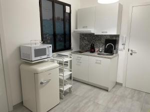 eine Küche mit weißen Schränken und einer Mikrowelle auf dem Kühlschrank in der Unterkunft Appartamento Suite Calipso in Pozzallo