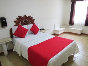 a bedroom with a large bed with red pillows at Hotel Arbis in Puebla