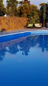 uma piscina azul com uma mesa e bancos em Casa da estrela sirius em Cabeço Chão