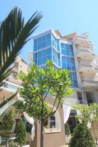 a tall building with a palm tree in front of it at Portafortuna Apartments in Sarandë
