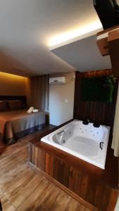 a bathroom with a tub in a room with a bed at Pousada Recanto dos Canyons in Praia Grande +204 photos