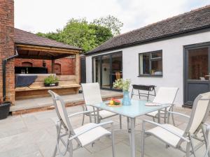 a patio with white chairs and a table and a building at Fields Farm in Draycott in the Moors