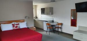 a bedroom with a red bed and a small kitchen at Ashburton's Regency Motel in Ashburton