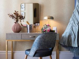 einen Schreibtisch mit einem Stuhl vor einem Spiegel in der Unterkunft Queens Hotel & Spa Bournemouth in Bournemouth