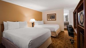 a hotel room with two beds and a television at Sturgis Lodge and Suites in Sturgis