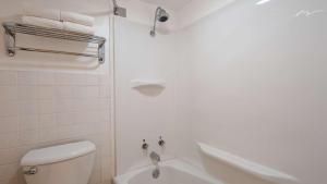 a white bathroom with a toilet and a bath tub at Sturgis Lodge and Suites in Sturgis +19 photos