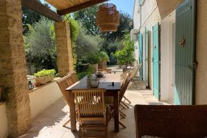 una mesa de madera y sillas en un patio en Chez Lydia - Rivière, Pont-du-Gard accès à pied !, en Castillon-du-Gard