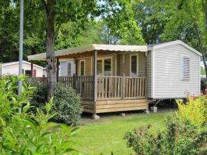 a tiny house with a porch in a yard at Camping du Mouchet in La Chapelle-Viviers