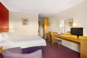 una camera d'albergo con un grande letto e una scrivania di Days Inn Hamilton a Hamilton