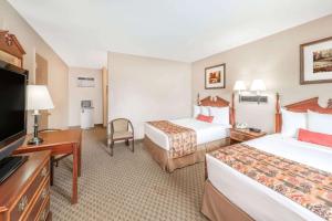 a hotel room with two beds and a flat screen tv at Days Inn by Wyndham Show Low in Show Low