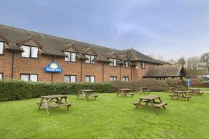 un grupo de mesas de picnic frente a un edificio en Days Inn by Wyndham Sevenoaks Clacket Lane en Westerham