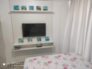 Confortável Flat com piscina de borda infinita na cobertura في كابيديلو: غرفة مع تلفزيون على جدار أبيض