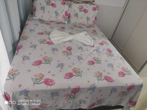 a bed with a flowery bedsheet with a bow on it at Confortável Flat com piscina de borda infinita na cobertura in Cabedelo