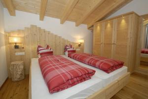 1 dormitorio con 2 camas, mantas rojas y almohadas en Mühlerhof, en Funes