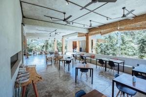a restaurant with tables and chairs and large windows at Surfing Temple Boutique Hotel in General Luna
