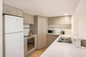 a kitchen with white cabinets and a white refrigerator at 68@CapeView in Busselton