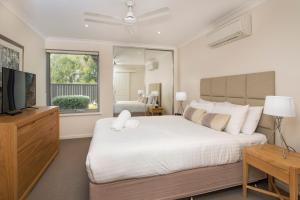 a bedroom with a large white bed and a television at 68@CapeView in Busselton