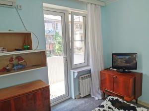 uma sala de estar com televisão numa cómoda e uma janela em Cozy apartment near big park em Baku