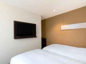 a bedroom with two beds and a flat screen tv at Hotel Vista Matsuyama in Matsuyama