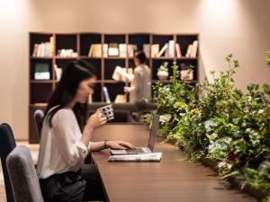 a woman sitting at a table with a laptop at Hotel Vista Matsuyama in Matsuyama