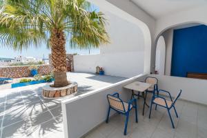 a patio with a table and chairs and a palm tree at Spiridoula Villa - Santorini Seaside Retreats in Perissa
