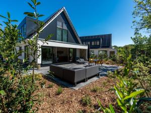 a modern house with a pool in the yard at Energy neutral villa with wellness area in Den Burg