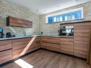 a kitchen with wooden cabinets and a brick wall at Energy neutral villa with wellness area in Den Burg