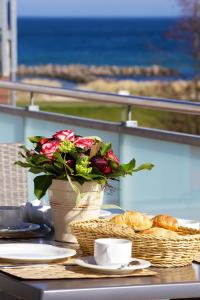 a table with a vase of roses and a basket of bread at Ostseeresidenz Schönberger Strand in Schönberger Strand