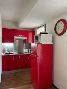 a red kitchen with a red refrigerator and a clock at La Comtesse in Saint-Gervais-les-Bains