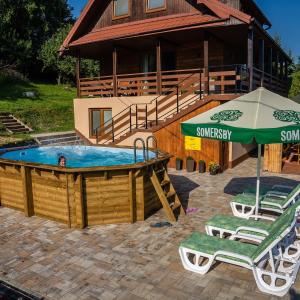 einem Pool mit Stühlen und einem Sonnenschirm vor einem Haus in der Unterkunft Willa Sulimówka - Noclegi Zakliczyn dom basen bania sauna SPA in Zakliczyn