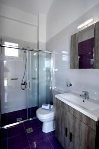 a bathroom with a toilet and a shower and a sink at GERANI apartments in Órmos